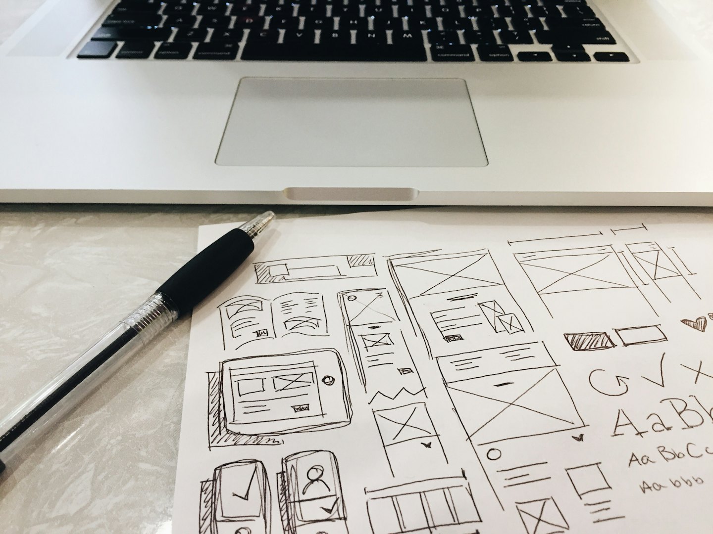 Handgezeichnete UI-Wireframes und Skizzen auf Papier mit einem Stift.