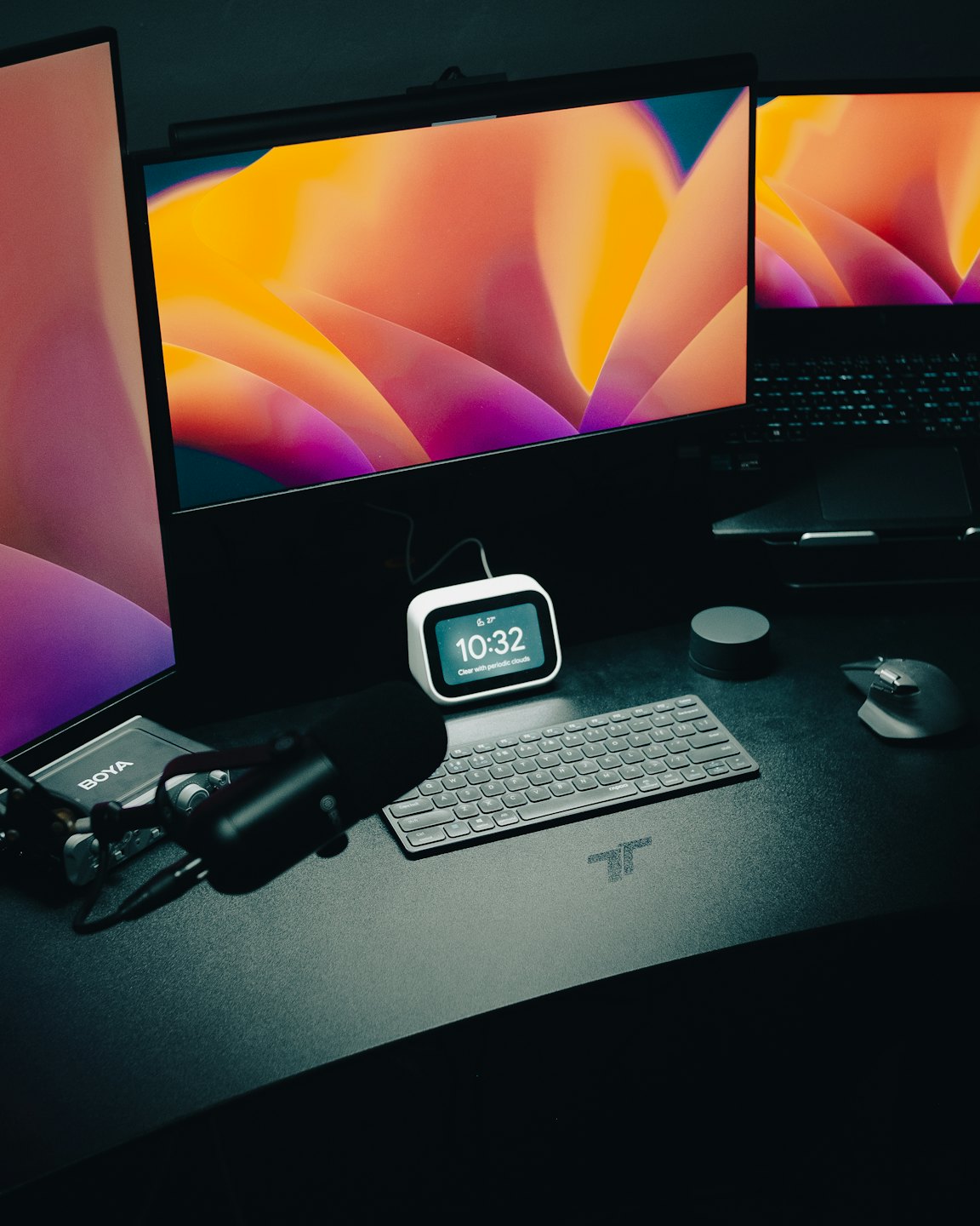 Schreibtisch mit Computermonitoren, Tastatur, Maus und Mikrofon.
